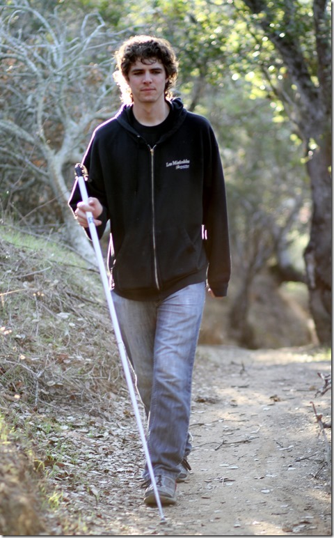 Brandon Biggs has Leber congenital amaurosis, specifically a mutation of the CRB1 gene. Pictured: Brandon walking a trail in the woods with his white cane. Photo courtesy Biggs family.
