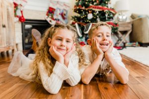 smiling girl and boy lying in front of Christmas tree