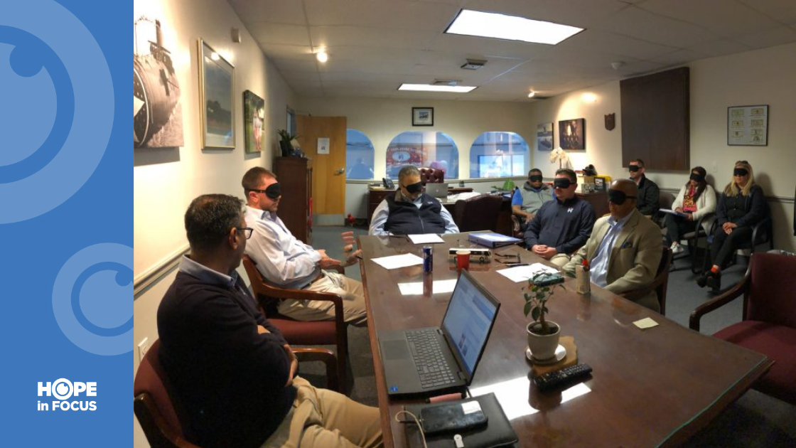Employees sitting in a meeting with blindfolds on