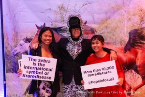 Luca Priebe in a zebra costume with two guests smiling next to him.