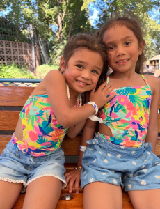 Malaya on the left and Iliana on the right. The girls are wearing matching outfits and smiling.