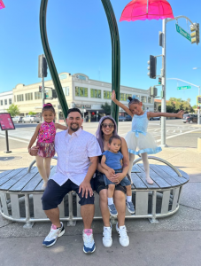 The Gonzales family smiling at the camera outside on a street corner. 