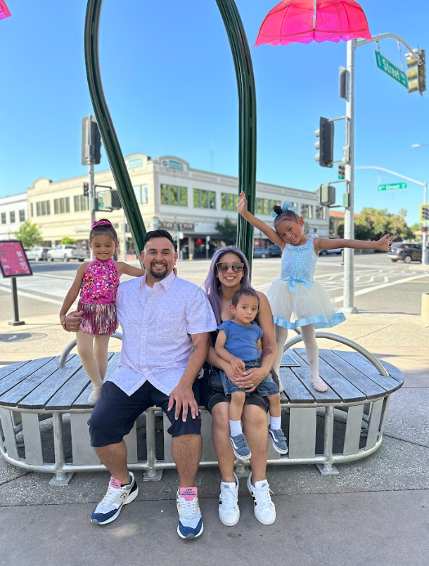 The Gonzales family smiling at the camera outside on a street corner.
