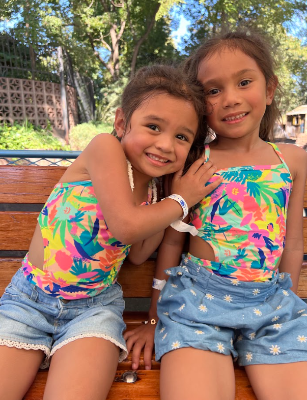 Malaya and Iliana wearing matching outfits and smiling for a picture.