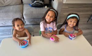 Amari on the left, Iliana and Malaya on the right. The siblings are sitting and smiling.