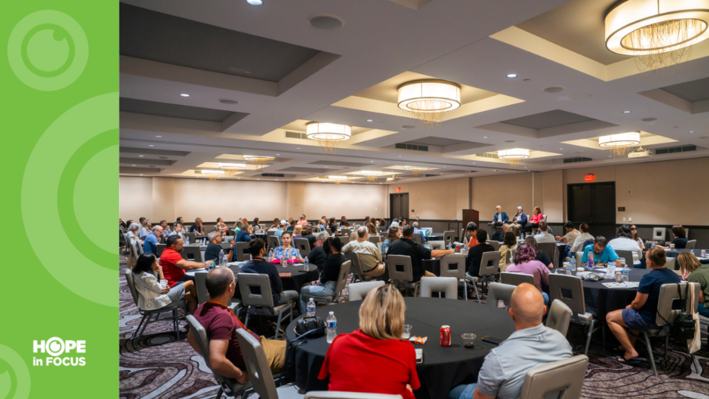 Audience seated at round tables listening to a panel discussion at the 2025 LCA Family Conference