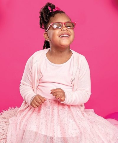 Jordynn Erwin smiling while wearing glasses against a pink background
