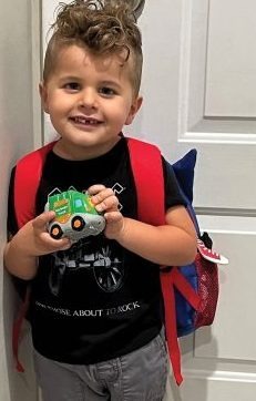Jace Broadbin wearing a backpack and holding a toy truck