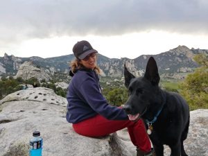 Michelle Ward Caton stands outdoors during a climbing trip with her first guide dog, Ryder, wearing climbing gear