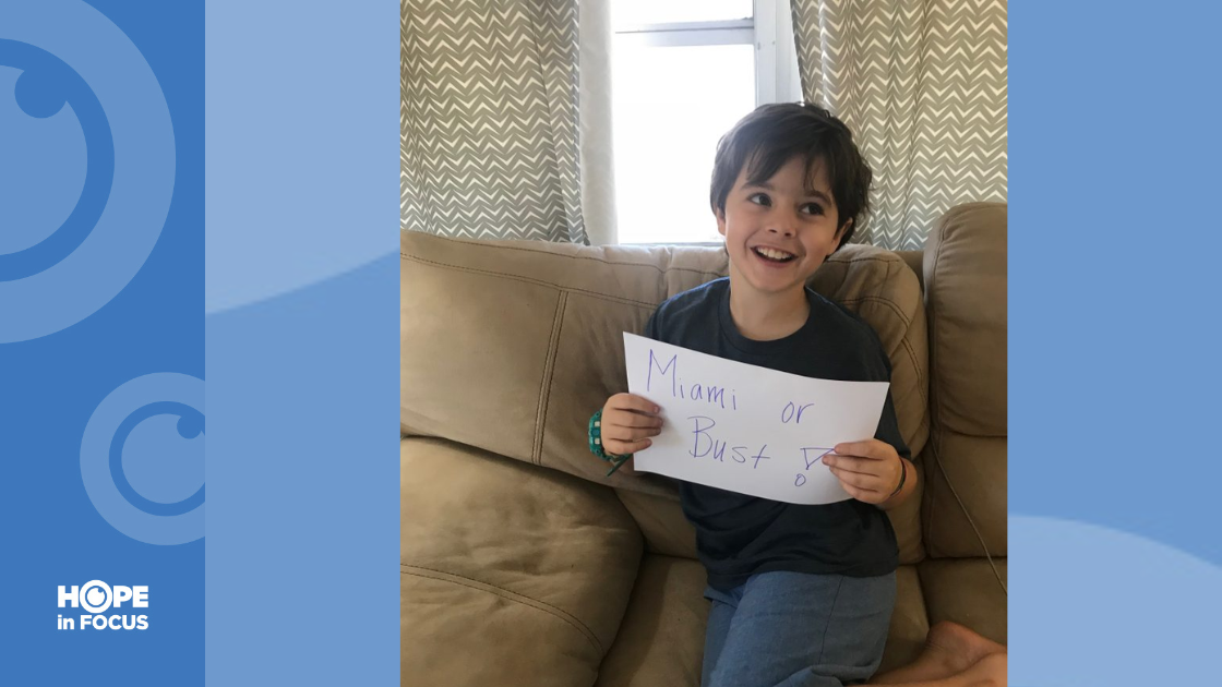 Creed excitingly holding a handmade sign saying "Miami or Bust!"