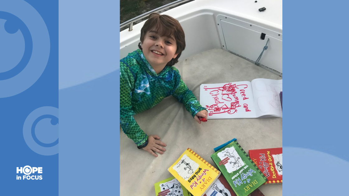 Creed reading and drawing after easily climbing onto a trailered powerboat