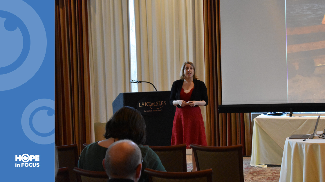 Nicole Kear in a red dress speaking at the podium at "A Rare Opportunity"