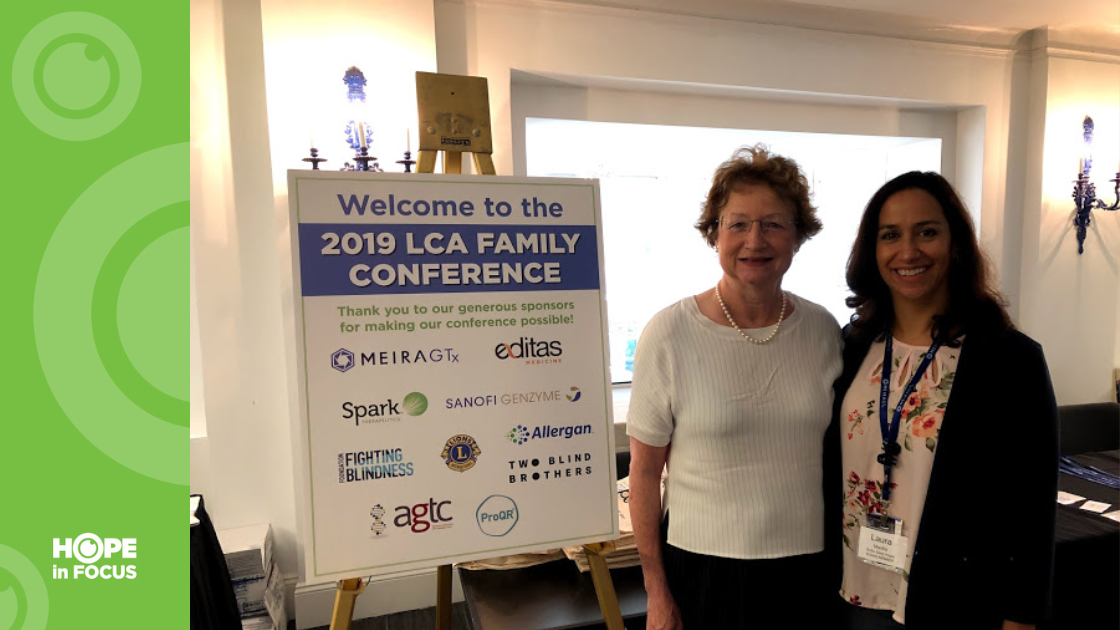 Dr. Katherine High and Laura Manfre next to a Welcome poster