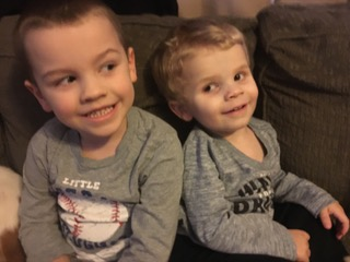 The two boys wearing grey shirts, sitting next to each other