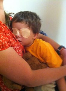 Creed with eye patches on his eyes, his mom is holding him