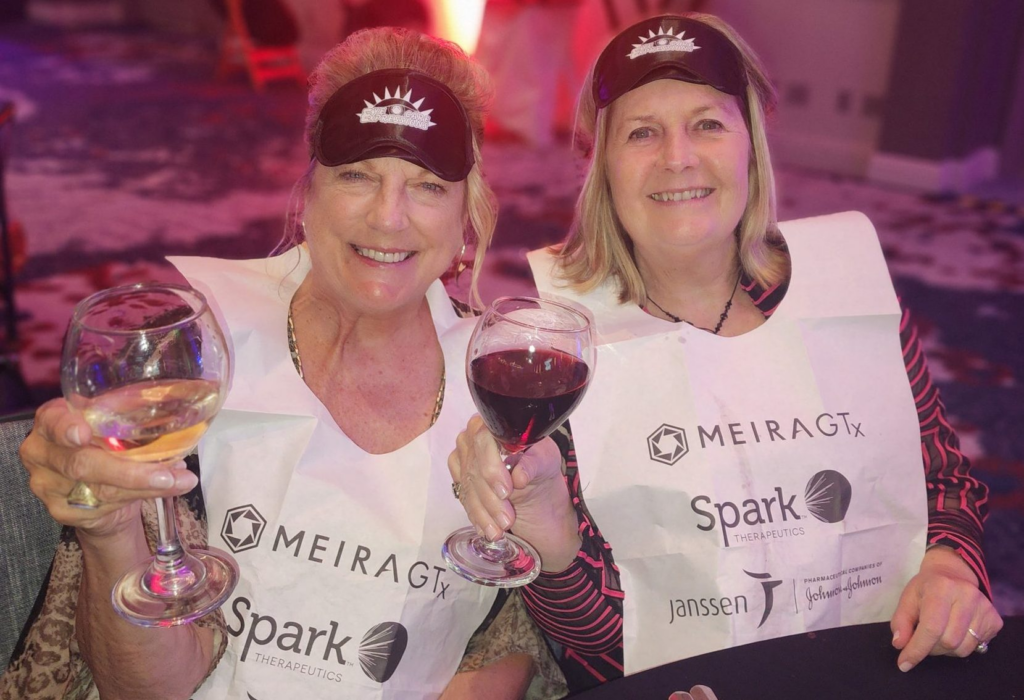 Image of two attendees holding up wine glasses.