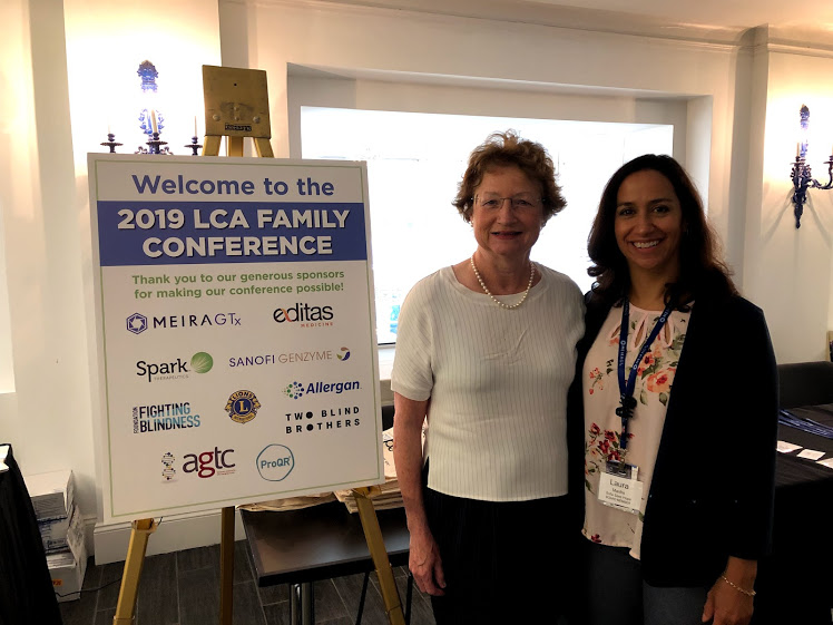 Dr. Katherine High and Laura Manfre next to a Welcome poster 