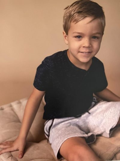 Noah sitting with a black shirt and grey shorts.