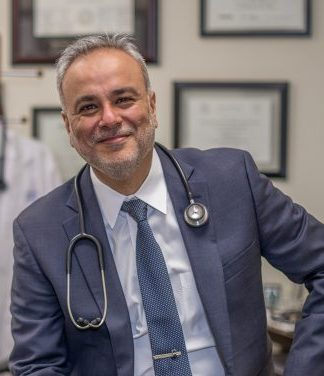 Saud Anwar in a blue suit with a stethoscope around his neck.