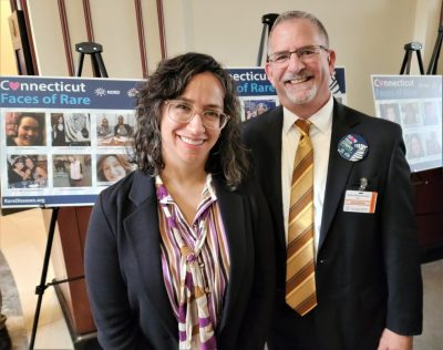 Laura (L) and Brian (R) in front of posters saying "Connecticut Faces of Rare".