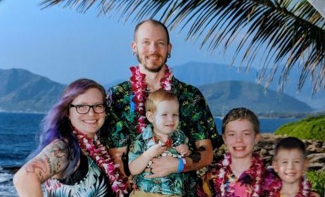 A family photo wearing Hawaiian shirts and flowers around their necks.
