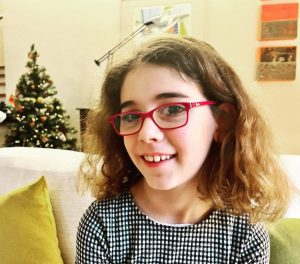 Vicky wearing red glasses and a black and white shirt.