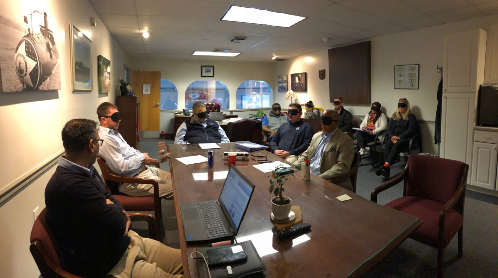 Employees sitting in a meeting with blindfolds on