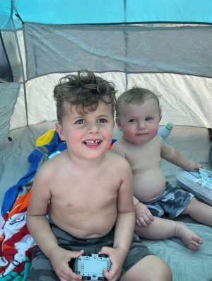 Jace and Gio sitting in a tent at the beach