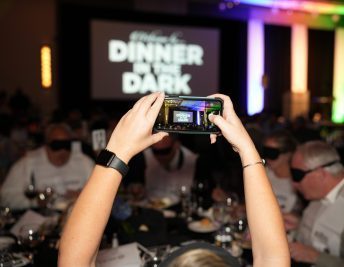 A person taking a picture of the Dinner in the Dark sign