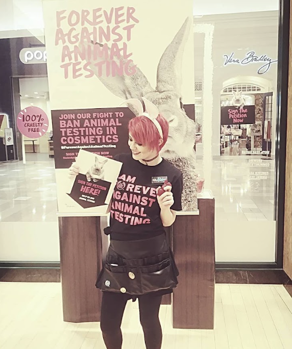 Ashley with pink hair holding up signs 